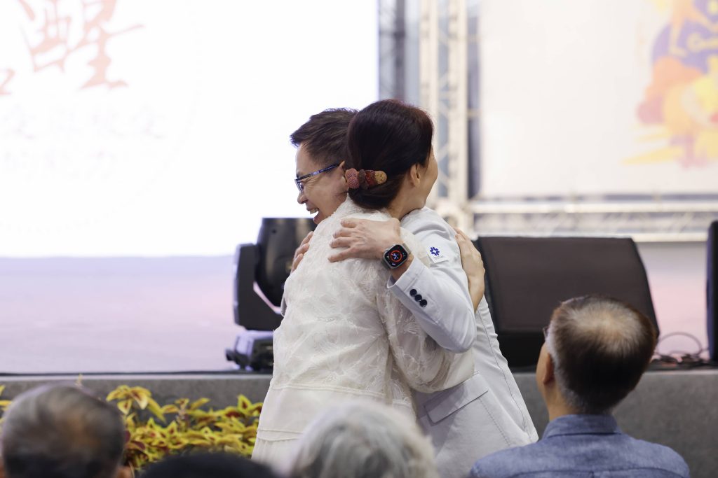 小樹傳愛協會發起人 Dammy 老師與外貿協會 黃志芳 董事長現場示範擁抱心運動。（社團法人小樹傳愛協會提供）